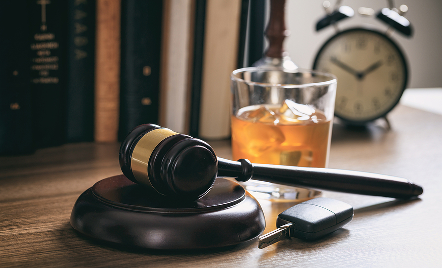 DUI concept. Law gavel alcohol and car keys on a wooden desk dark background